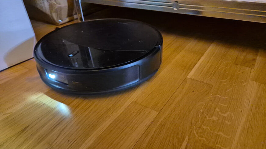 Der Saros 20 navigiert durch ein möbliertes Wohnzimmer mit vielen Stuhl- und Tischbeinen.